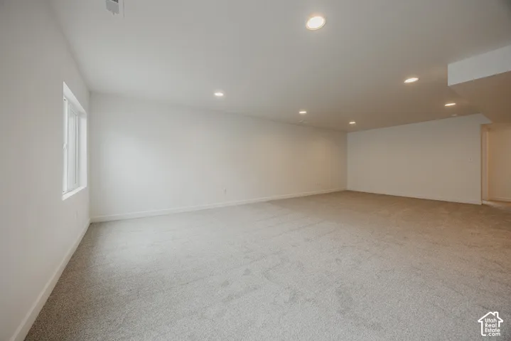 Spacious room featuring light-colored carpeting, recessed ceiling lighting, and a single window