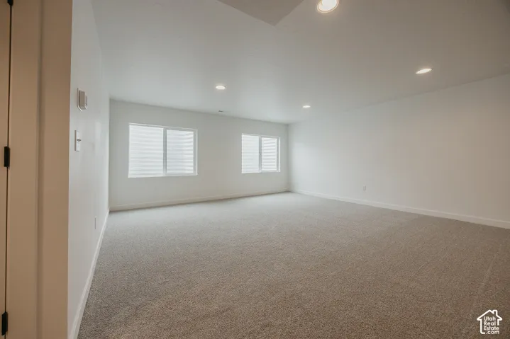 Recessed lighting, light-colored carpeting, white wall paint, multiple windows, and horizontal blinds