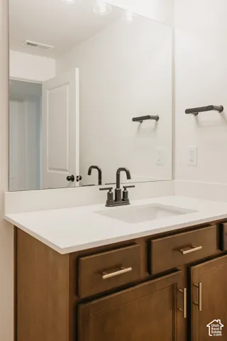 Bathroom vanity featuring wood-finish cabinetry, a white countertop, an undermount sink, and a black-finish faucet