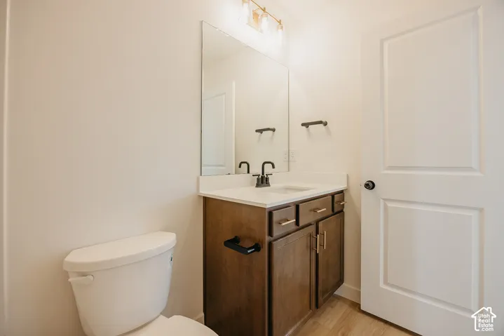 White toilet with a dark wood-finish vanity, white countertop, and black fixtures