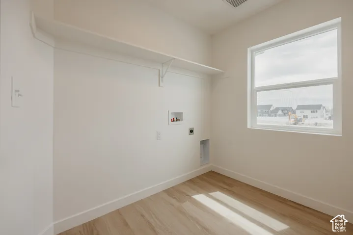 Utility space featuring wood-finish flooring, a white fixed shelf, and a large window