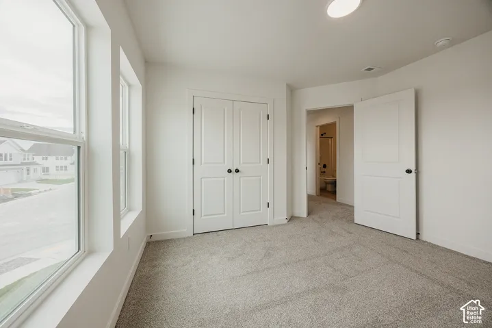 Carpeted room with multiple windows, bi-fold closet doors, and recessed lighting