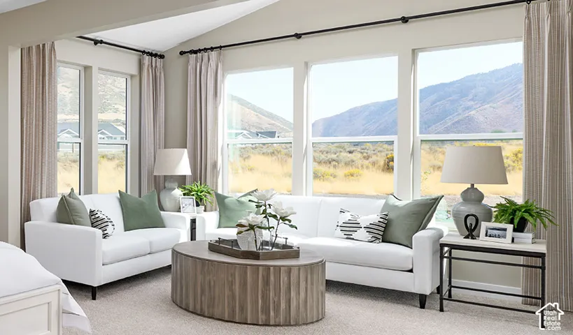 Vaulted ceiling with recessed lighting, large windows, light-toned carpeting, and a wood-finish coffee table