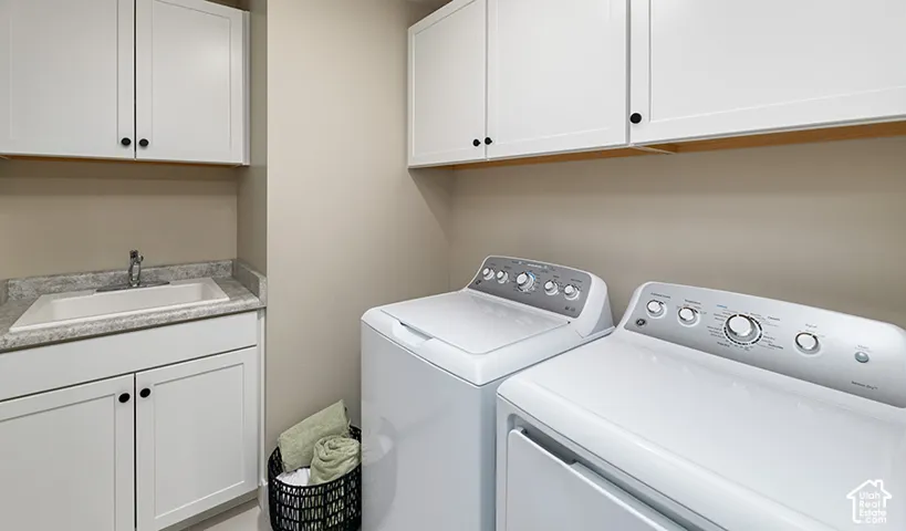 Laundry area featuring white cabinetry, integrated sink, and countertop