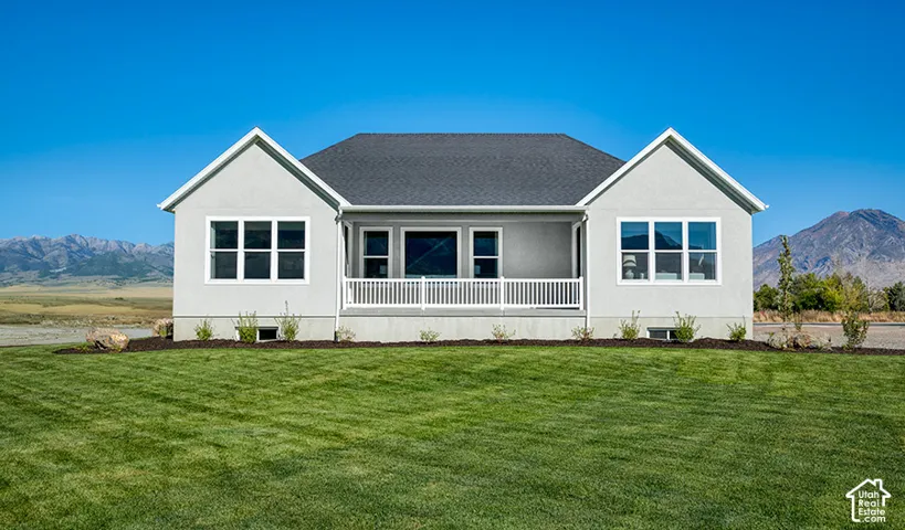 Pitched roof residence with light-toned stucco siding and a covered front porch featuring white railings