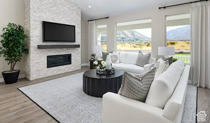 Stone-clad fireplace with hearth, wood-finish flooring, recessed lighting, and expansive windows
