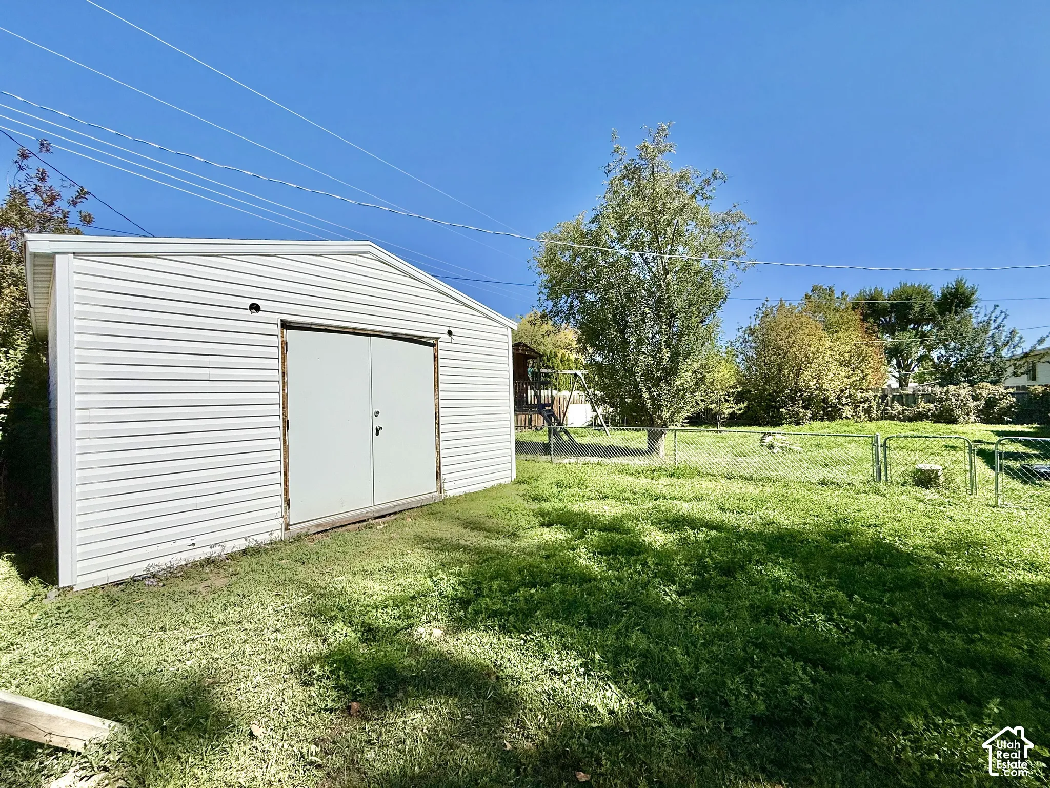 Detached storage shed with white horizontal siding and a gambrel roof
