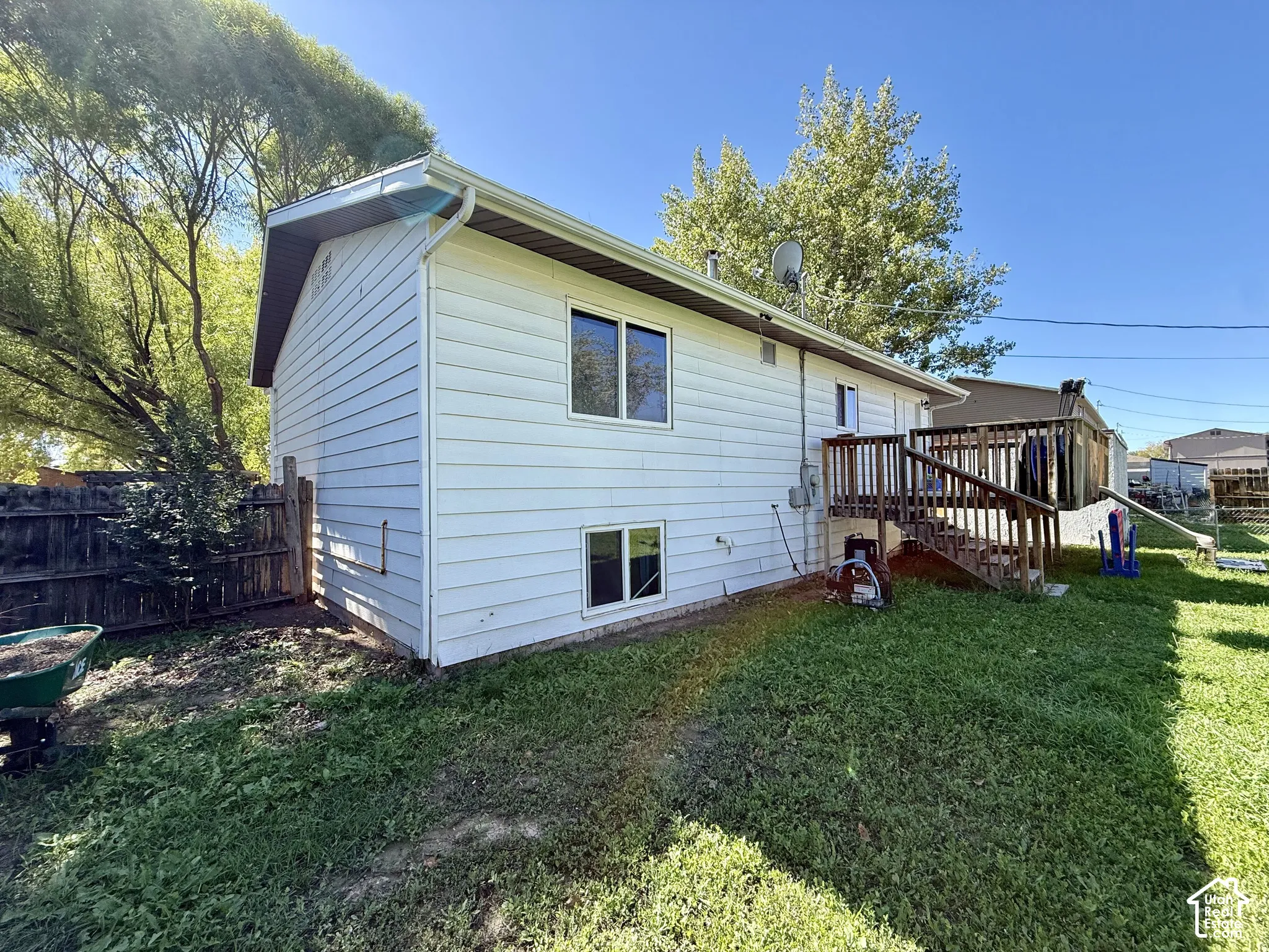 White siding exterior with a multi-level wood deck, white-framed windows, and a fenced perimeter