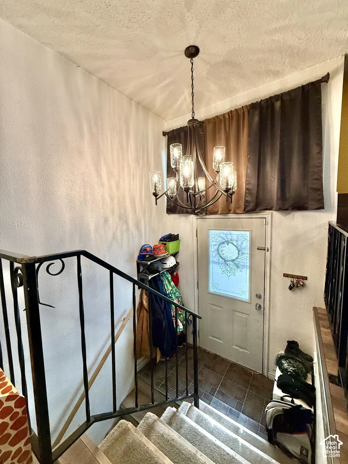 Staircase featuring carpeted treads, wrought iron railing, and a multi-light chandelier