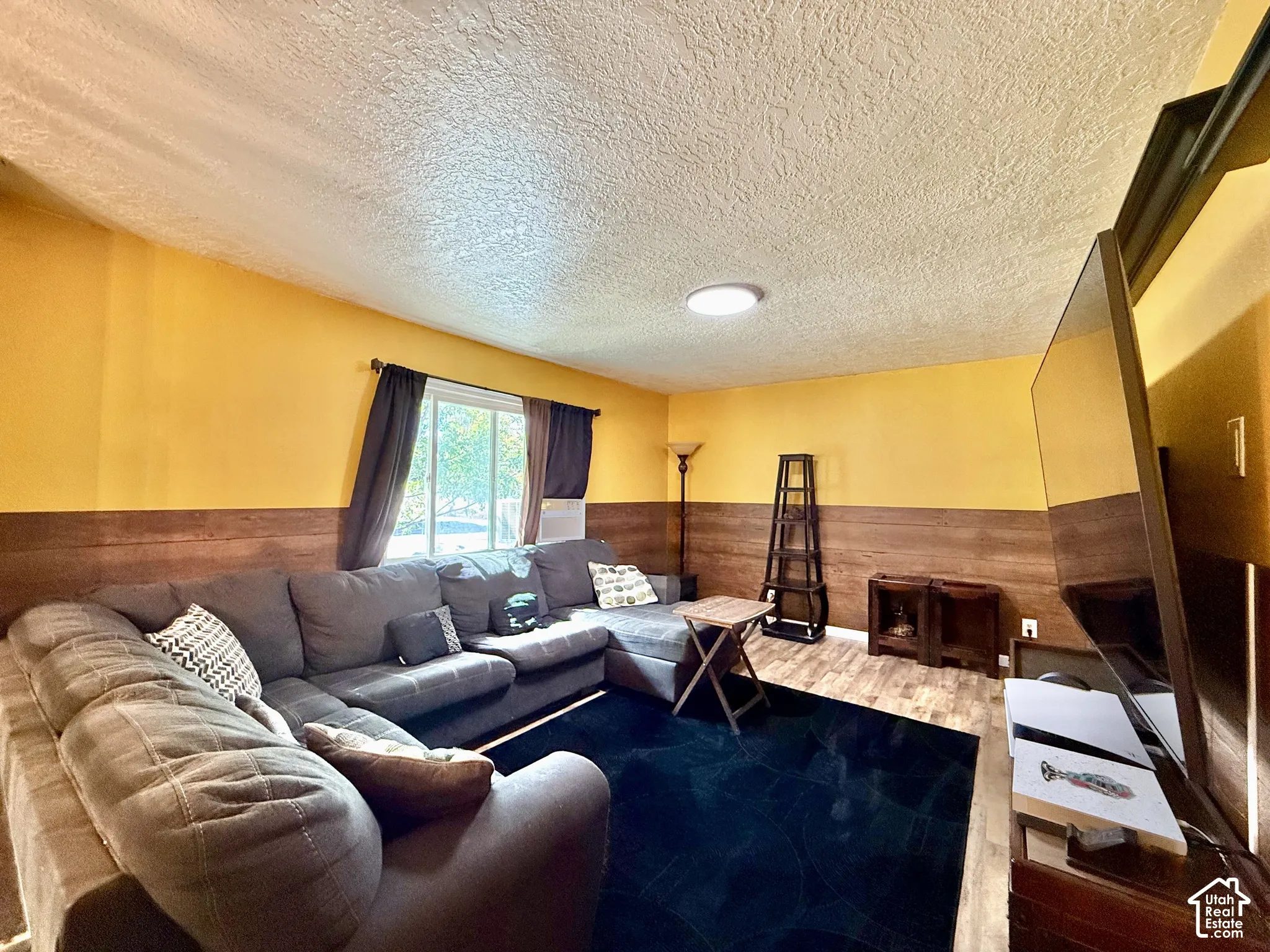 Textured ceiling, wood-finish wall paneling, and a flush-mount overhead light fixture