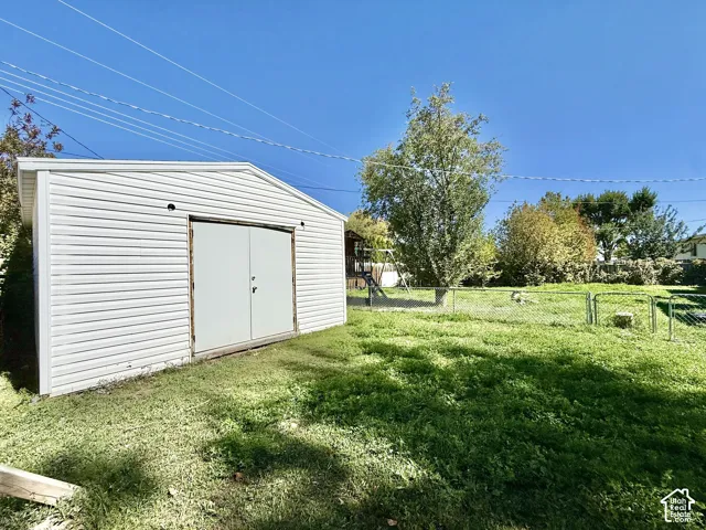 Detached storage shed with white horizontal siding and a gambrel roof