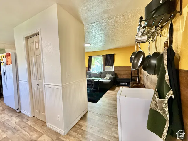 Wood-finish flooring, white paneled wainscoting, bi-fold closet doors, and a wall-mounted pot rack