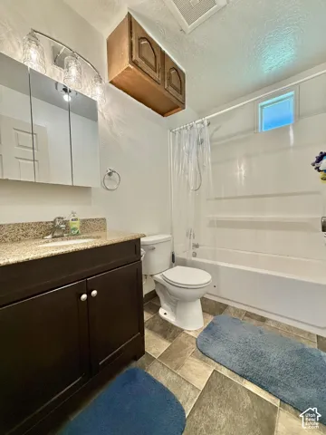 Dark wood-finish vanity with a speckled countertop, undermount sink, and a mirrored medicine cabinet