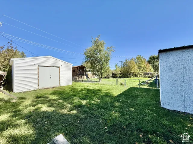 Expansive lawn with a white storage shed and mature trees