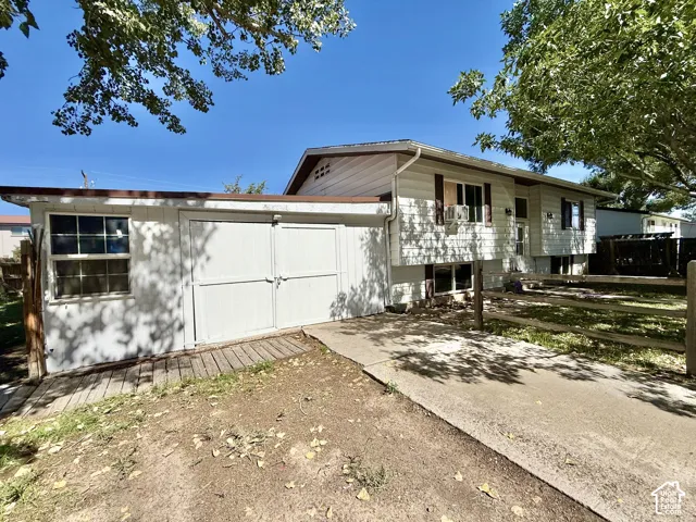 Split-level residence featuring white siding, brown window shutters, and a concrete driveway