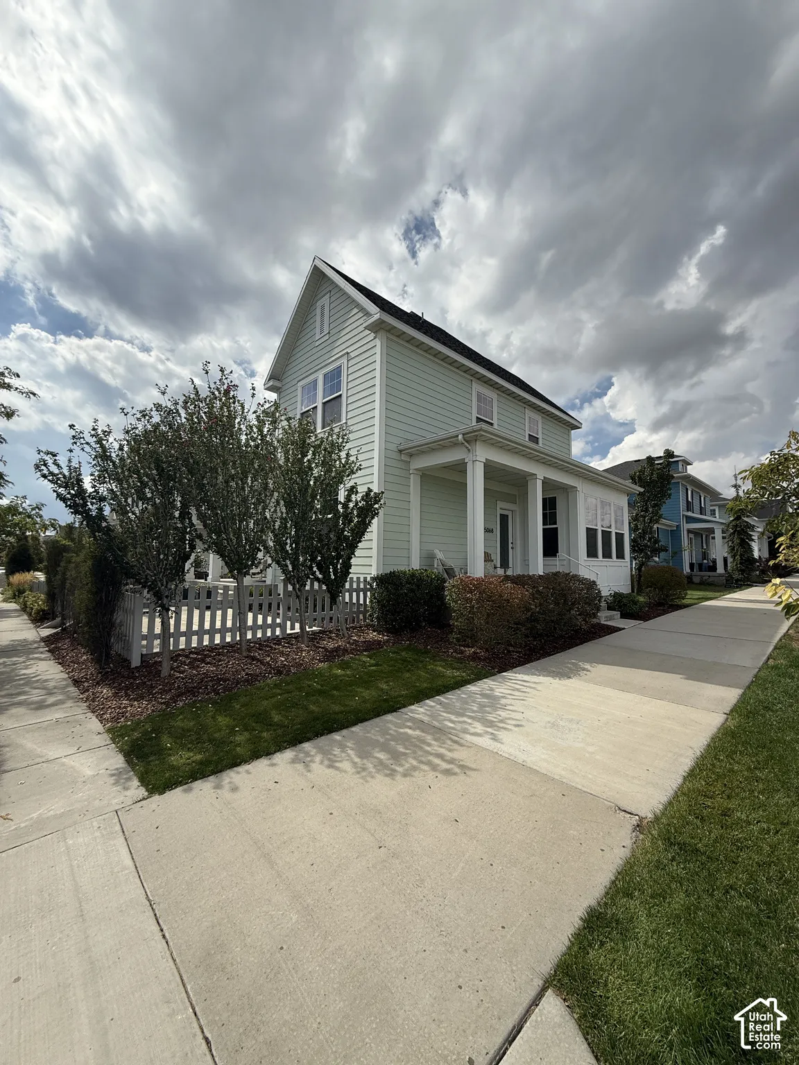 Two-story residence with light green siding and a covered front porch featuring white columns