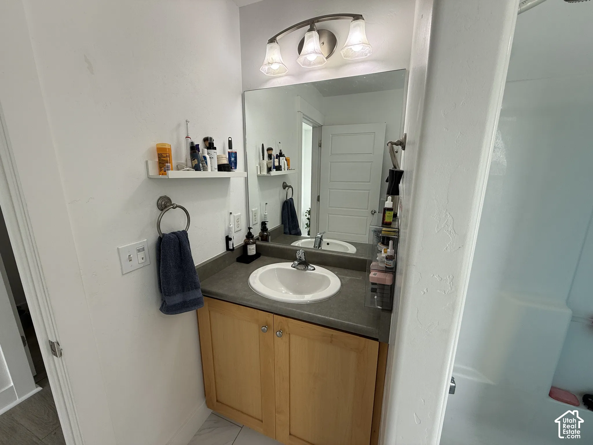 Single vanity with a light wood finish cabinet and a grey countertop