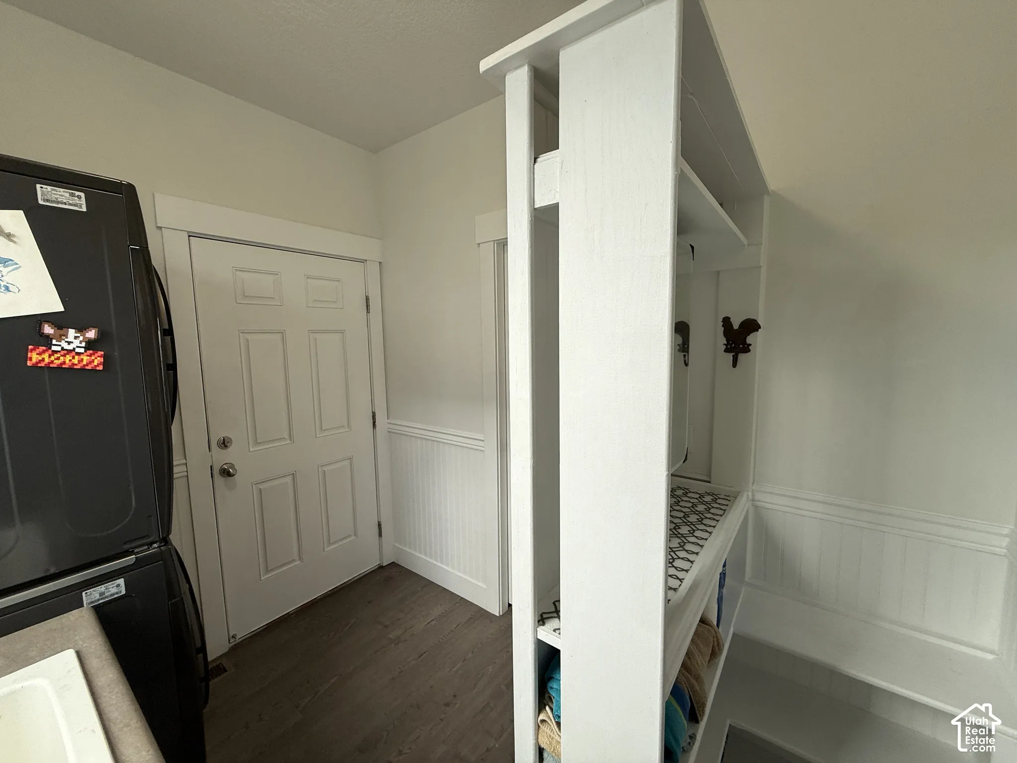 Built-in shelving unit, beadboard wainscoting, wood-finish flooring, white paneled door