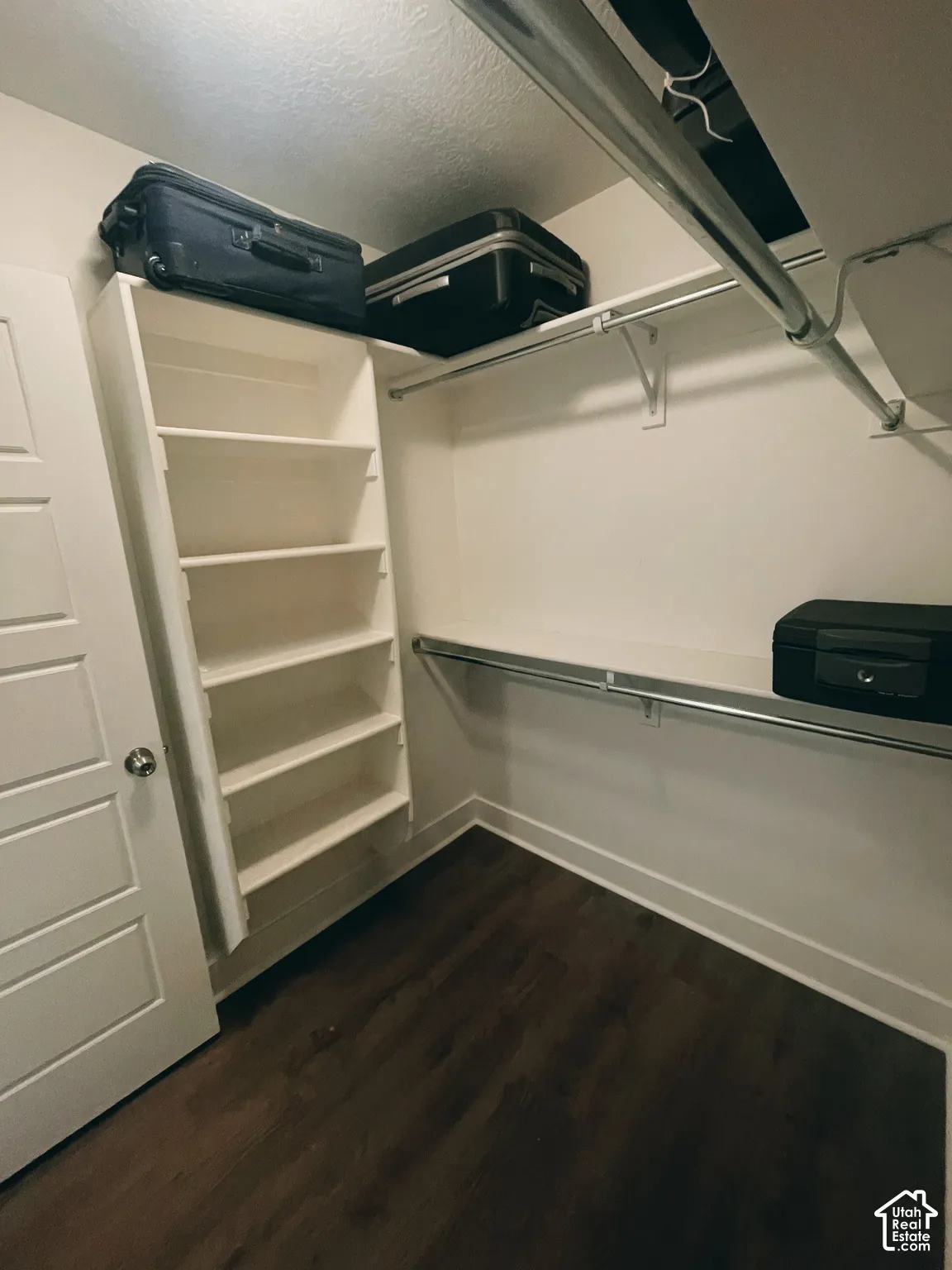 Built-in shelving, two hanging rods, upper storage shelf, and wood-finish flooring