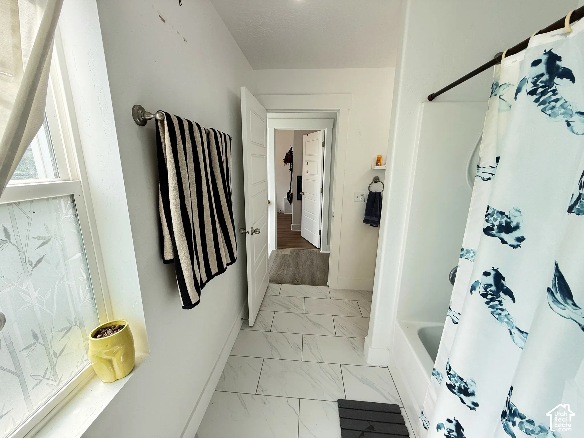White tile flooring and a built-in bathtub with a shower rod
