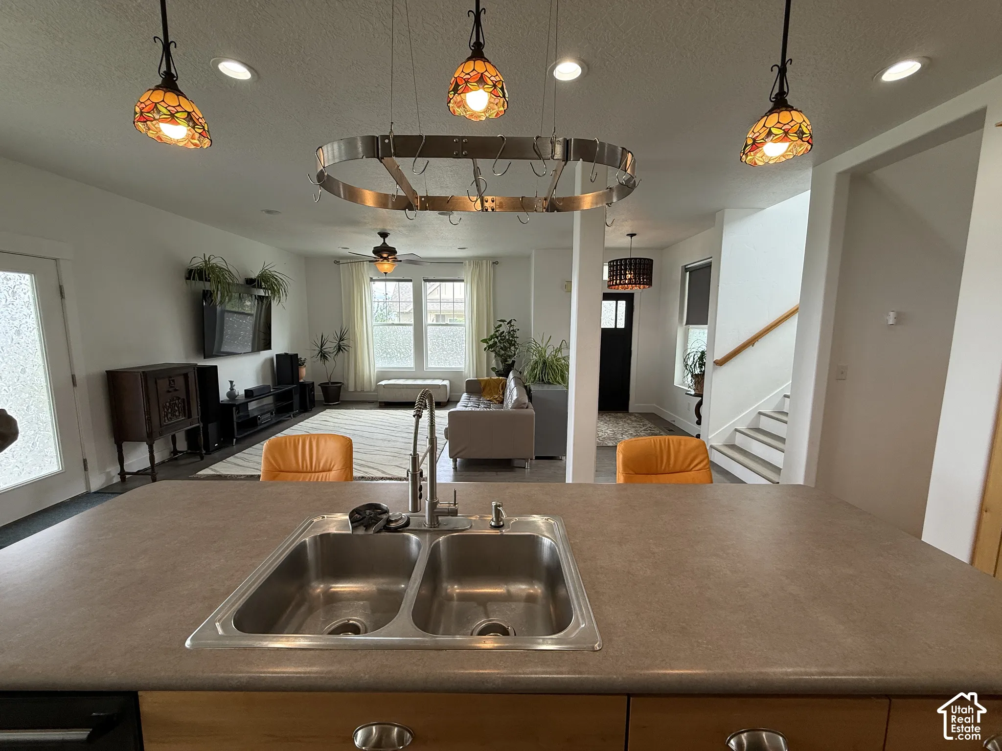 Kitchen island with a double basin stainless steel sink, brushed nickel faucet, and a pot rack with integrated lighting