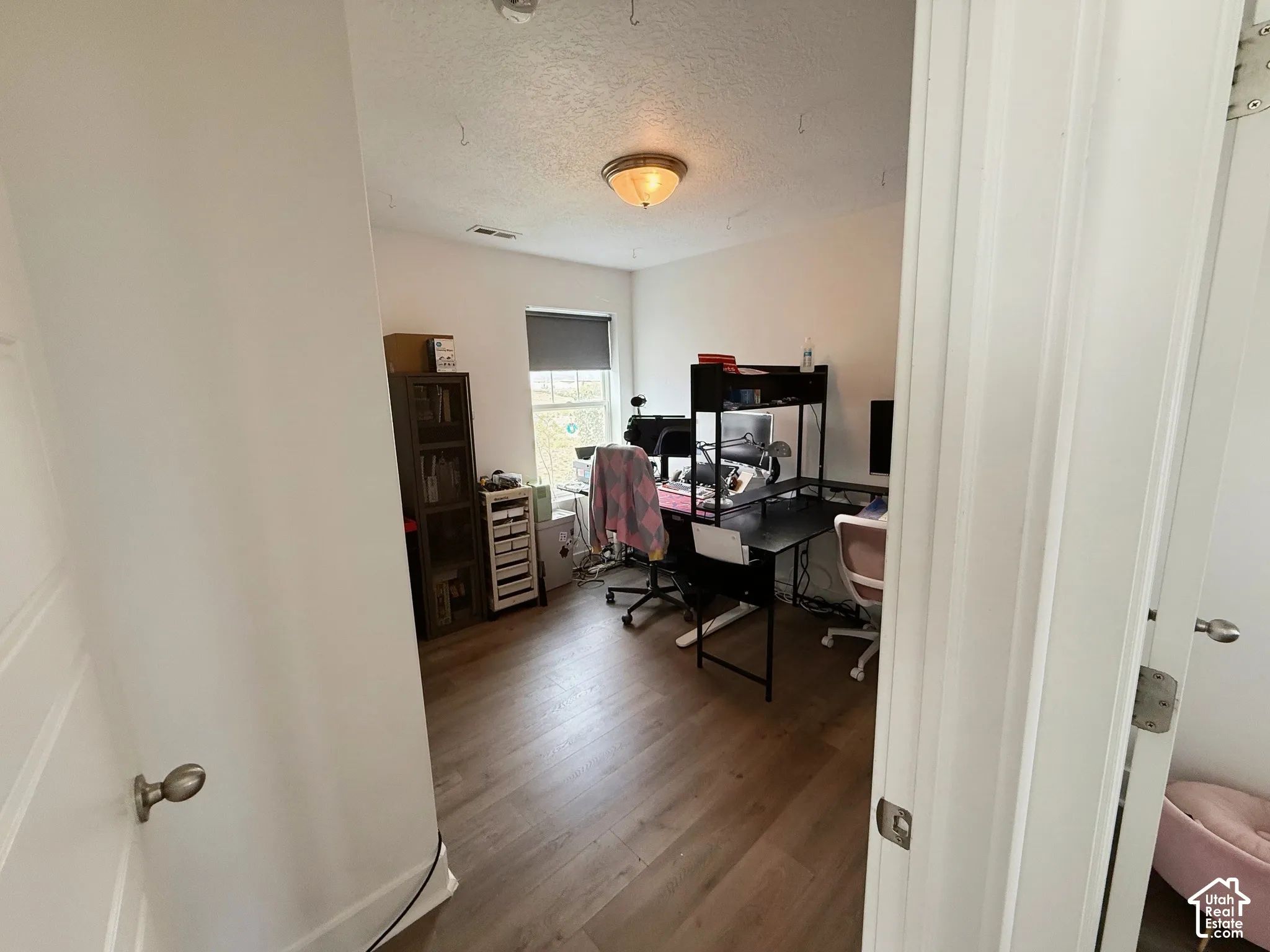Wood-finish flooring, white walls, and a ceiling-mounted light fixture