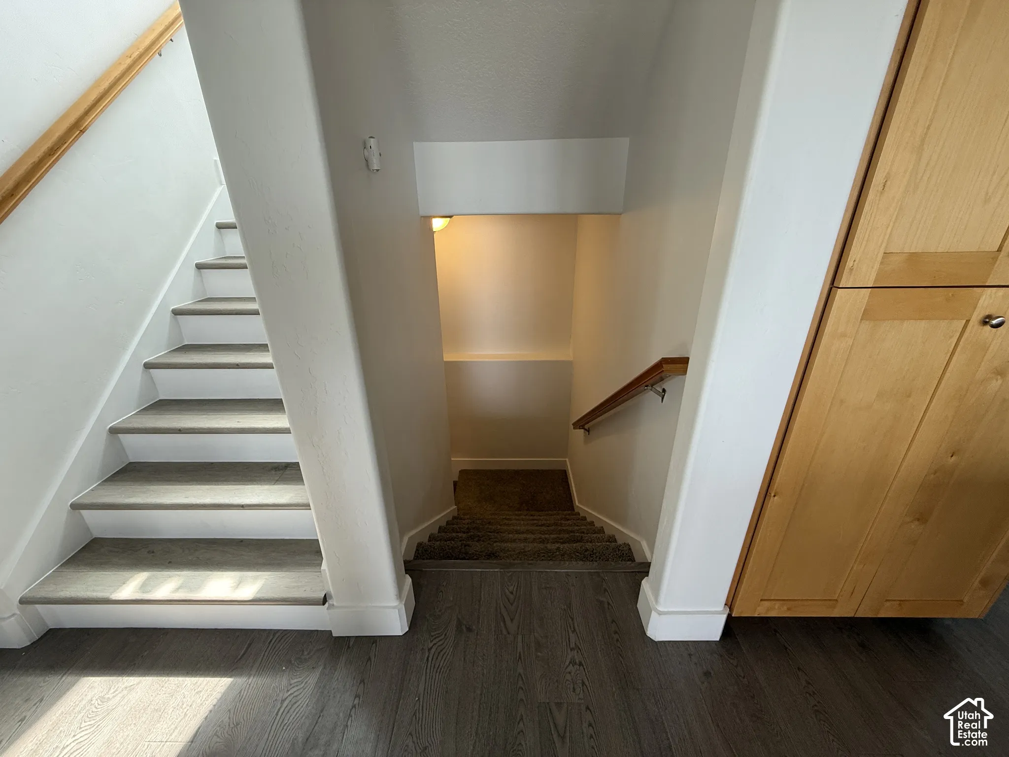Wood-finish flooring, built-in natural wood cabinetry, and a carpeted staircase with wood handrails