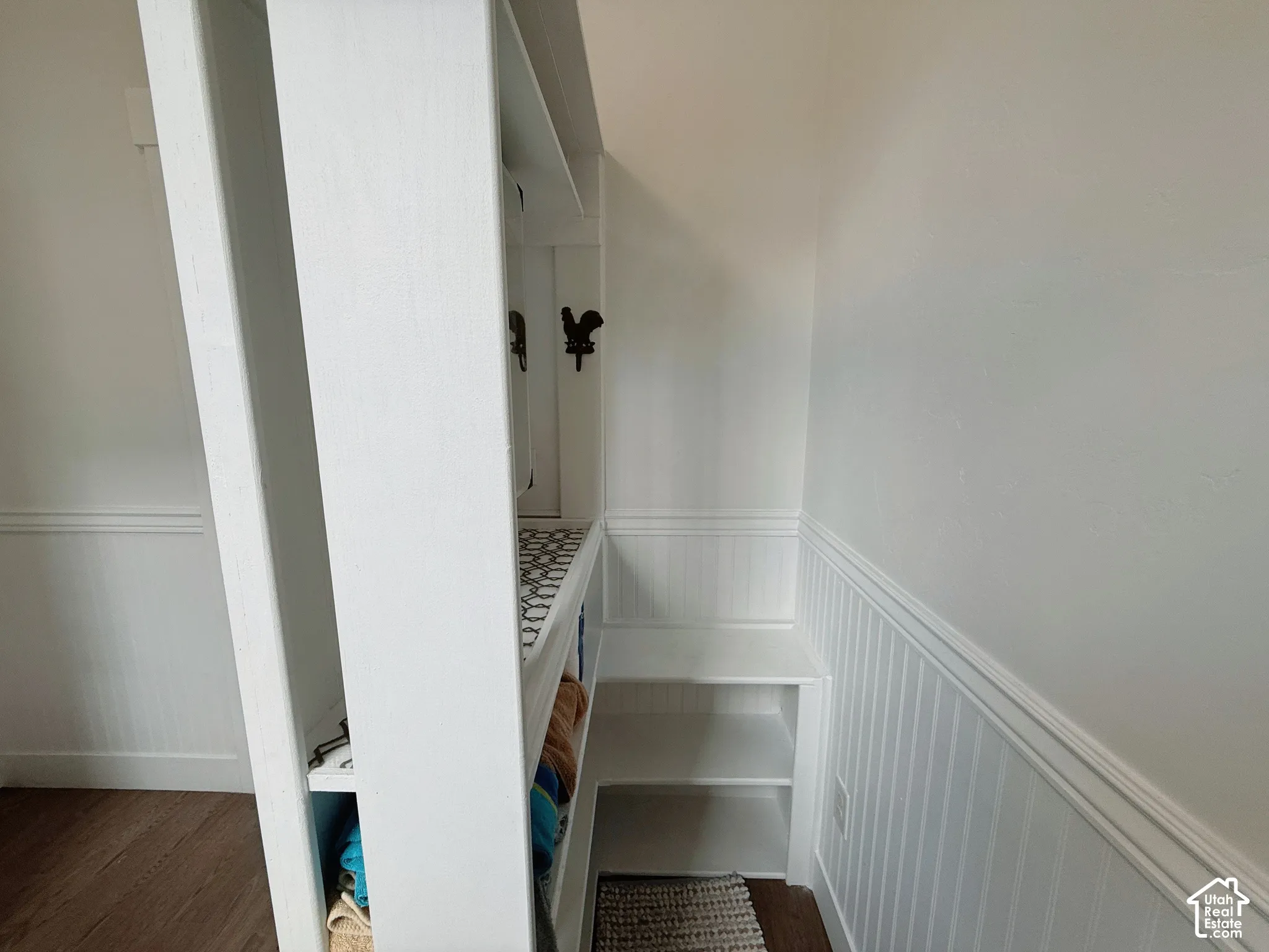 Built-in storage unit with open shelving and decorative hooks, accenting wood-finish flooring
