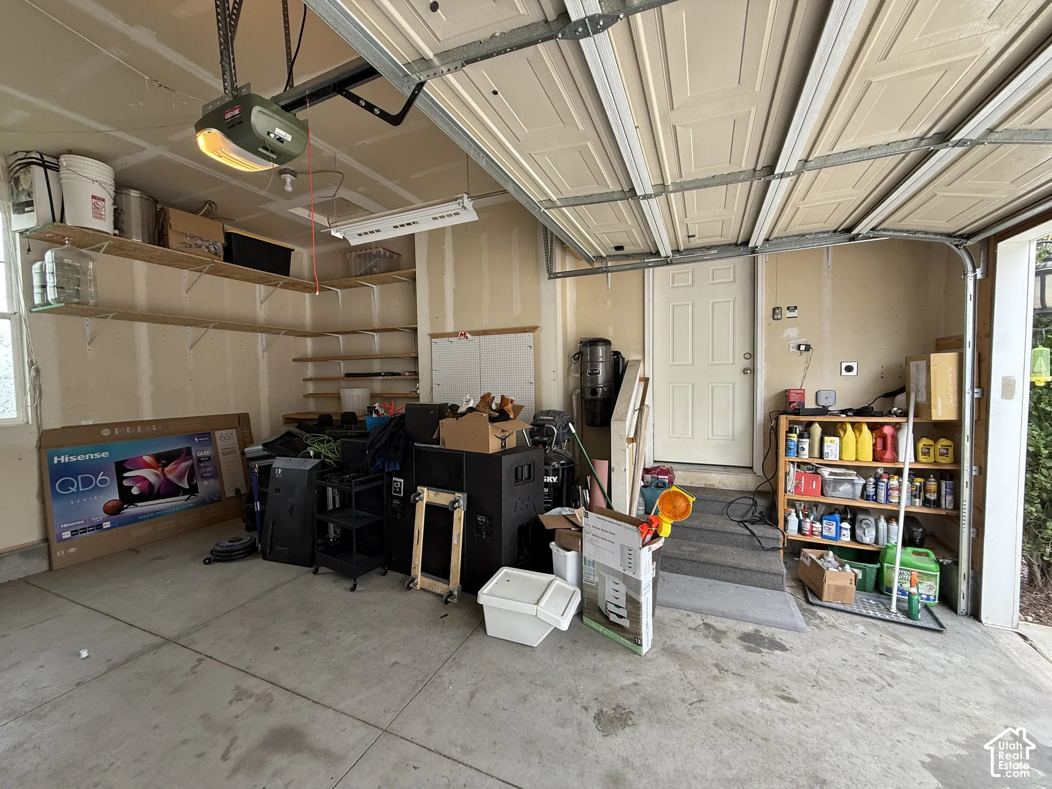 Attached garage featuring a panel overhead door, concrete flooring, and built-in wall shelving