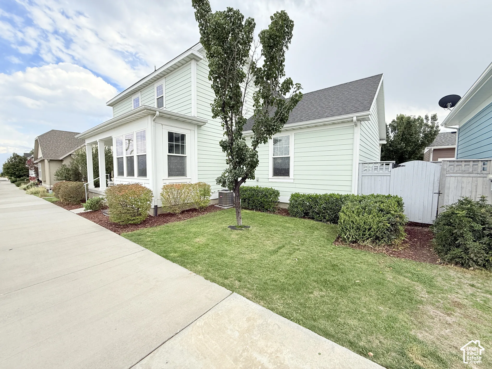 Light green horizontal siding exterior with a covered front porch and multi-pane windows