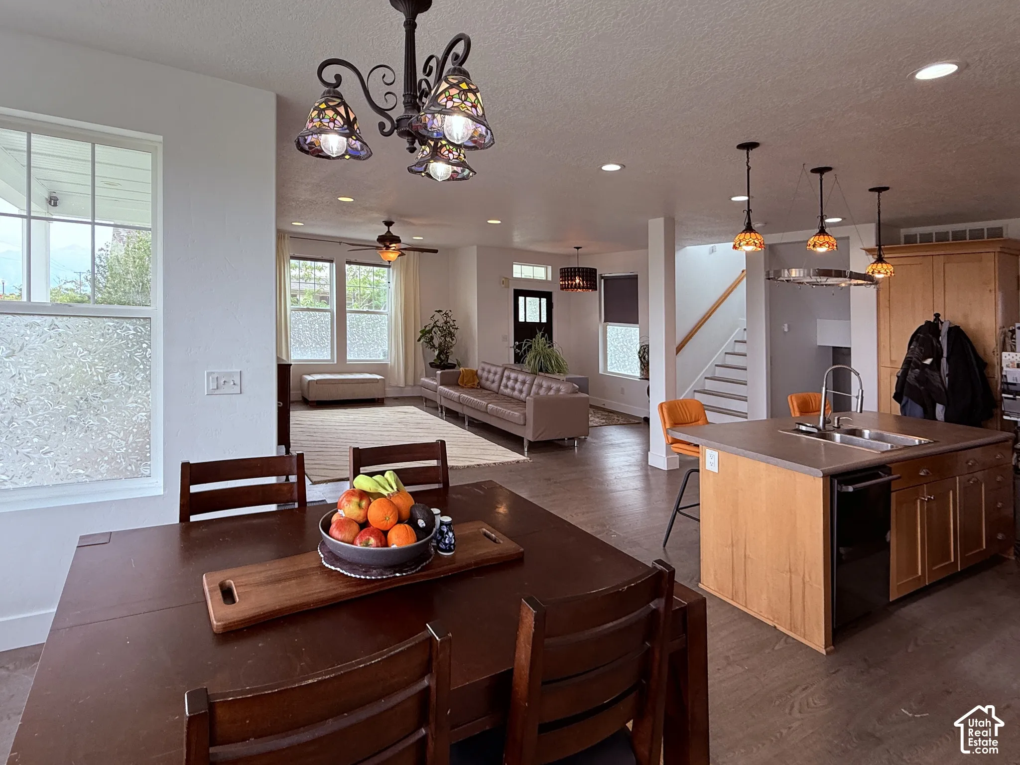 Open-concept living space featuring wood-finish flooring, recessed lighting, and a kitchen island with integrated sink