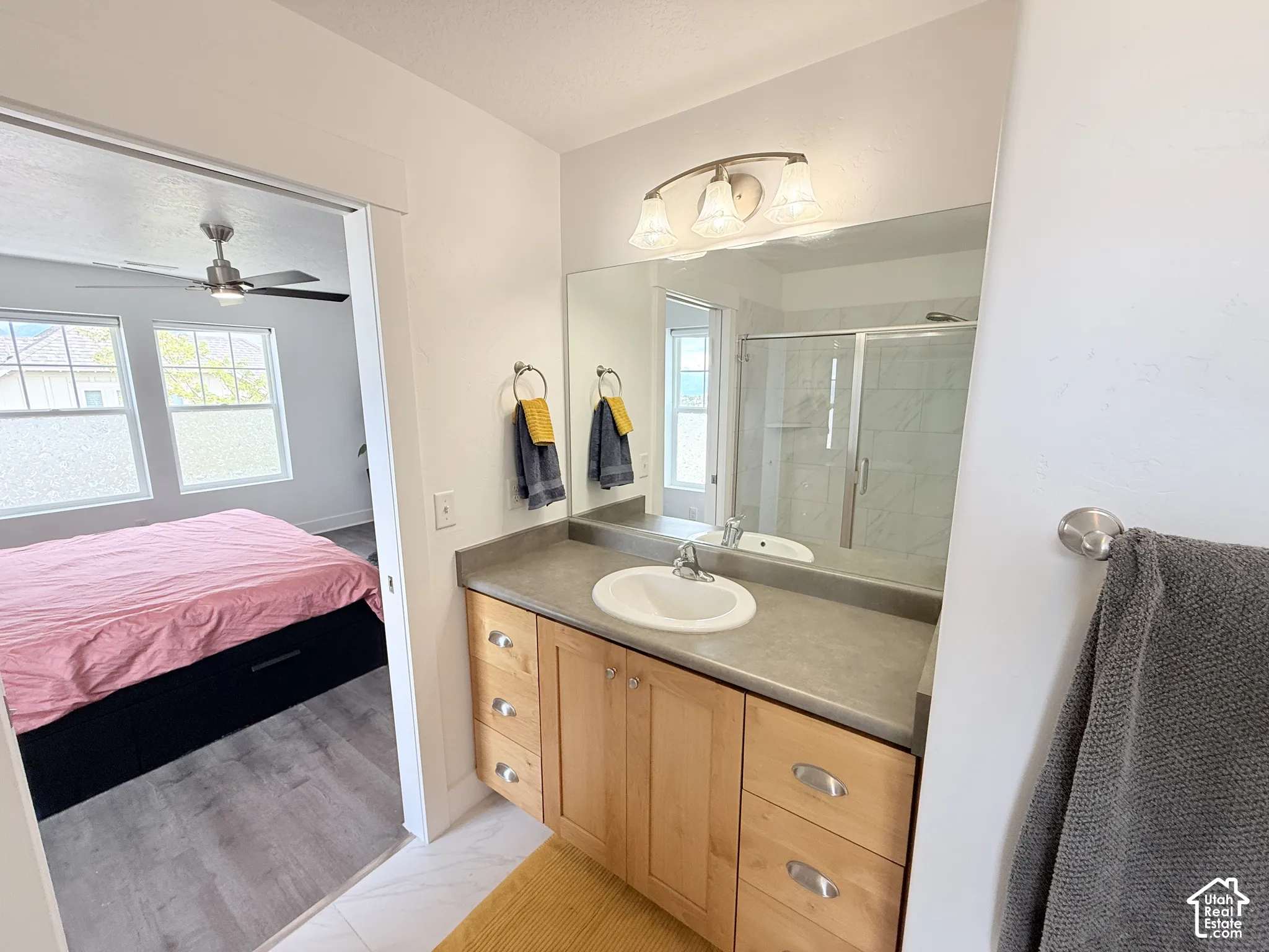 Bathroom featuring a single vanity with wood cabinetry, a large mirror, and a glass-enclosed shower