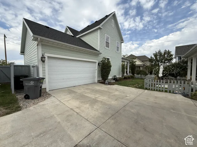 Two-story siding exterior with a pitched roof, attached garage with a panel door, and a concrete driveway