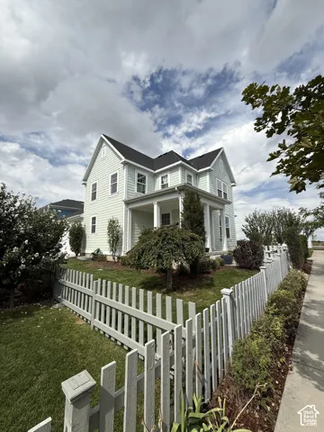Two-story residence with a covered front porch featuring column supports, light-colored siding, and a dark shingle roof