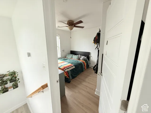 Room featuring wood-finish flooring, a ceiling fan, and a window