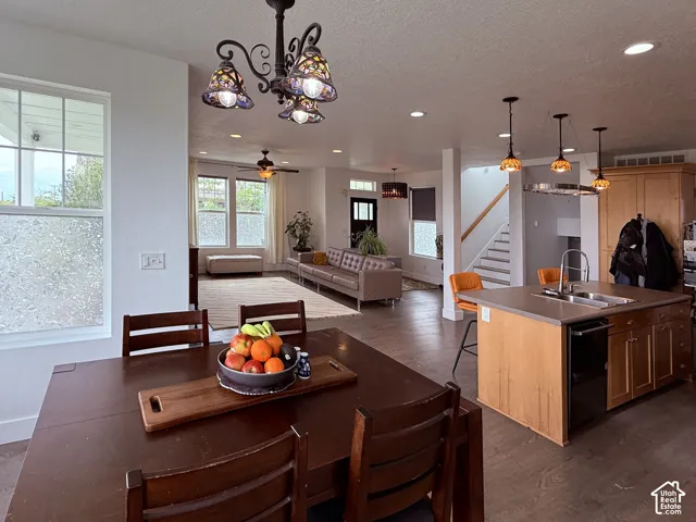 Open-concept living space featuring wood-finish flooring, recessed lighting, and a kitchen island with integrated sink