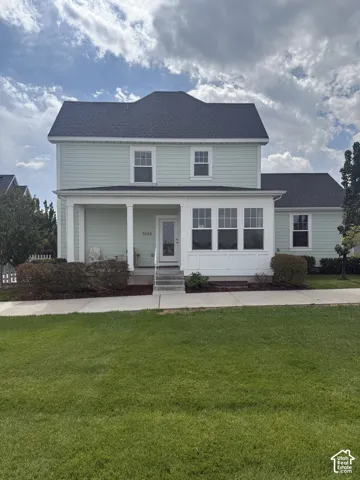 Two-story residence featuring light-colored siding, a dark shingle roof, a covered porch with white columns, and multiple windows