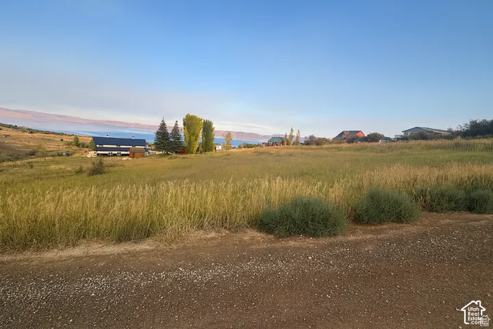 Expansive open land with a gravel foreground and distant water body