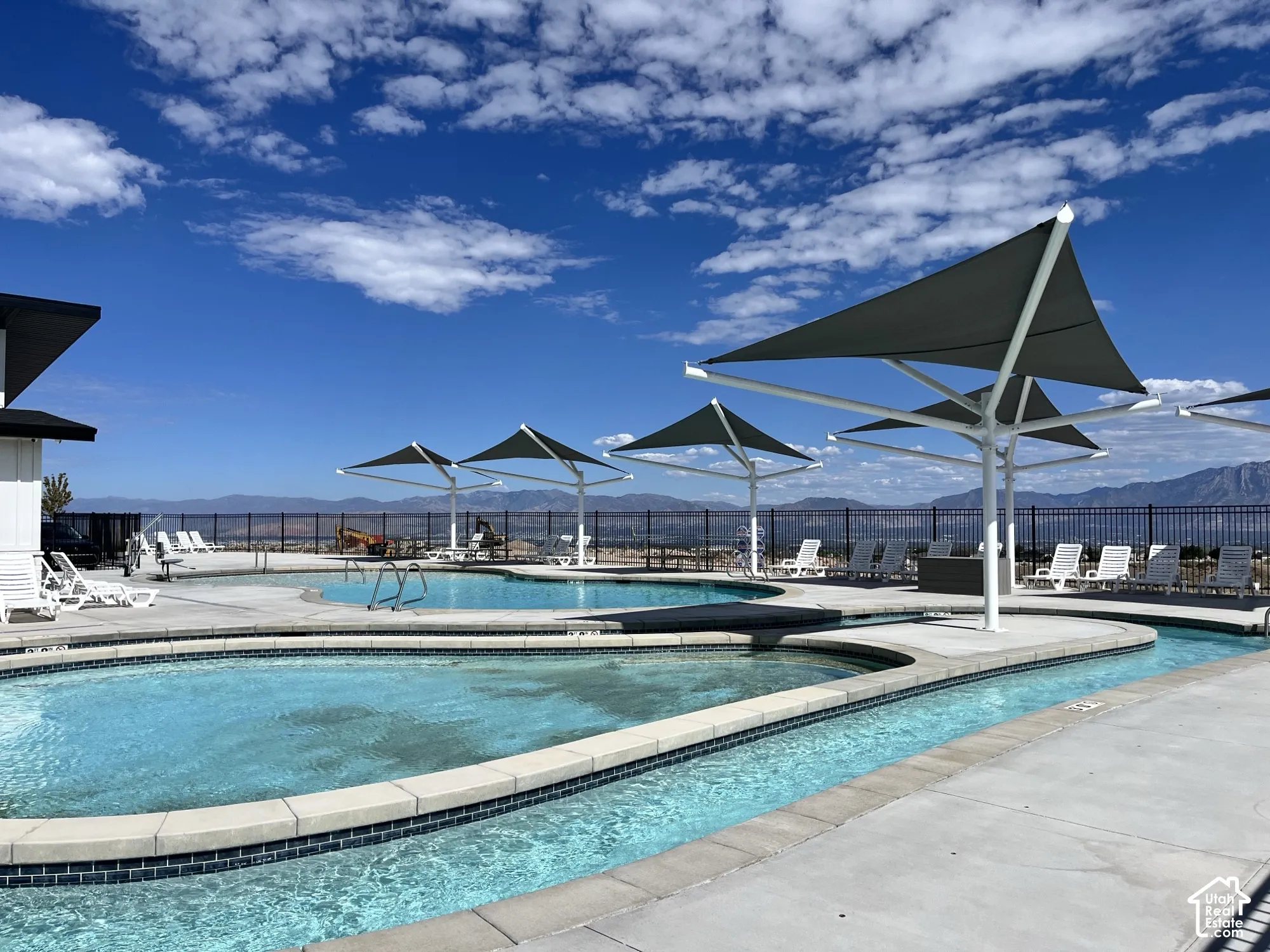 Resort-style pool with a winding water feature, multiple shade structures, and surrounding concrete decking
