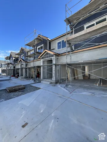 Row of contemporary townhomes under construction, featuring dark vertical siding and light-colored stucco exteriors