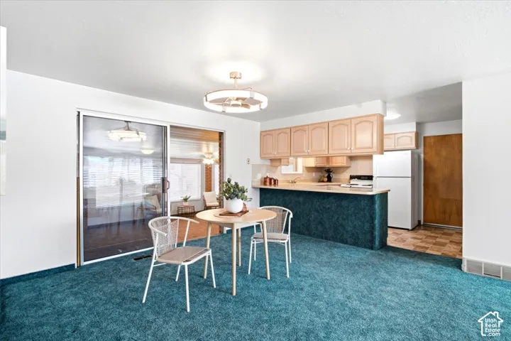 Kitchen featuring light wood-finish cabinetry, white appliances, and a pass-through counter