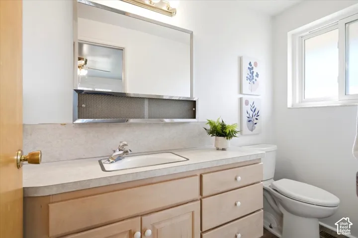 Primary Bathroom vanity with an integrated sink, polished chrome faucet, and wood-finish cabinetry, shower is behind the door.