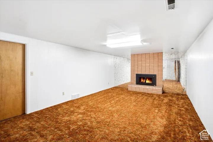 Brick fireplace with a metal insert, white paneled walls, and built-in overhead lighting