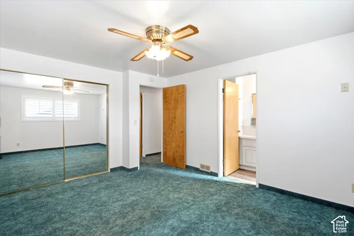 Primary Bedroom, mirrored sliding wardrobe doors, ceiling fan with light fixture, wood doors, and white interior walls
