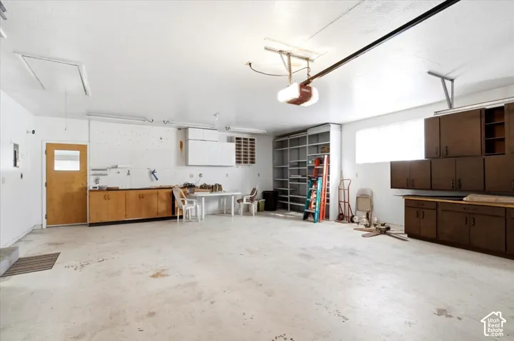 Spacious garage featuring concrete flooring, built-in shelving, and extensive cabinetry