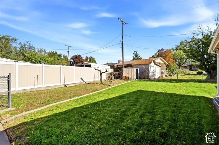 Expansive backyard featuring a lush lawn, privacy fencing, and a detached shed