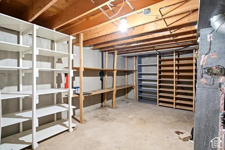 Exposed wooden ceiling beams, concrete flooring, and multiple built-in shelving units