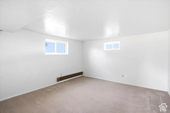 Carpeted flooring, white painted walls, and two fixed windows