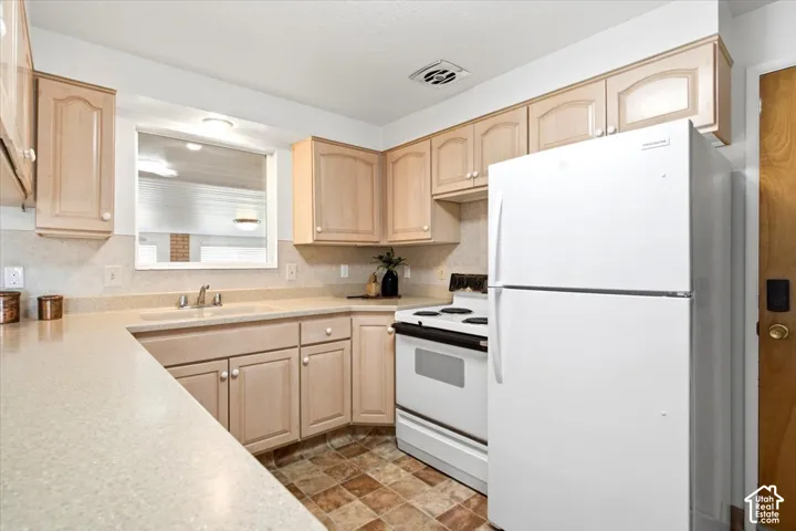 Kitchen featuring light wood-finish cabinetry, light-toned countertops, and a white oven/range