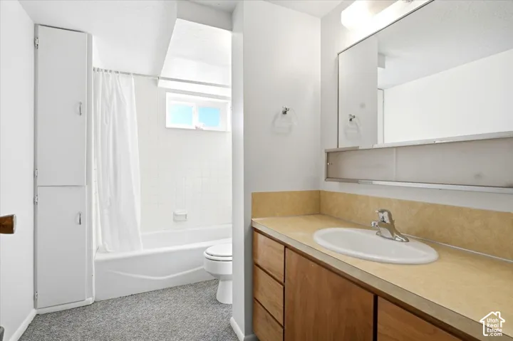 Vanity with an integrated sink and wood-finish cabinetry, full-width mirror, and overhead lighting